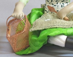 Garden Girl 2 holds basket and trowel in her leather garden gloves