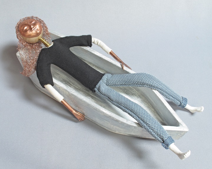 art doll Current Drift reclines in her small wooden boat