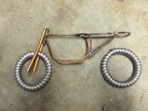 beginning copper frame for doll sized motorcycle and wheels of electrical conduit