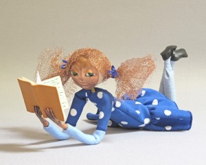 reclining art doll figure with book