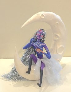Weaving Dreams celestially colored art doll seated on the crescent moon