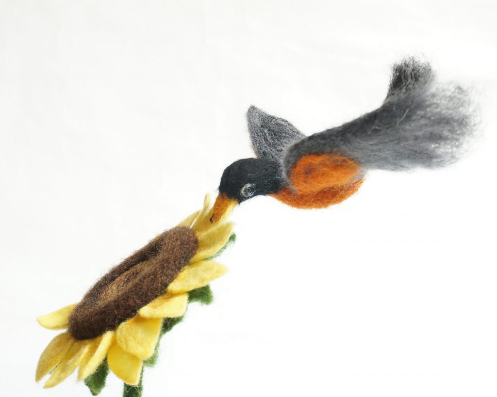 Helping Sunflower is needle felted wool sculpture over a wire and quilt batting armature form. Anthropomorphic raccoon, mouse and robin work together to help a sunflower