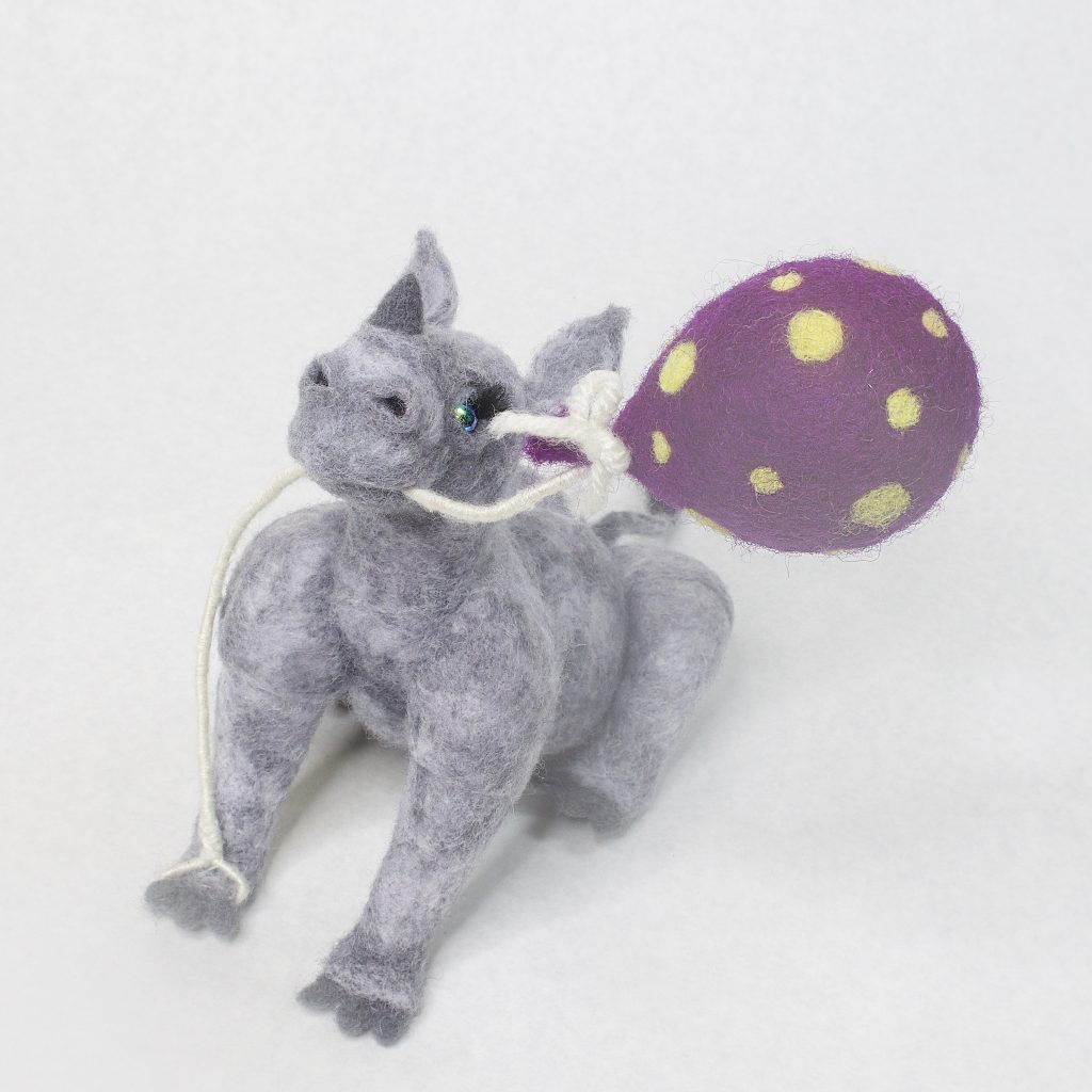needle felted anthropomorphic baby rhinoceros sculpture with polka dot balloon