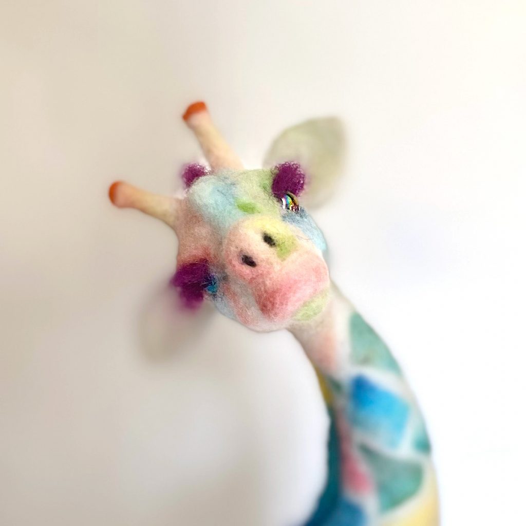 close up of Peace "tye dye" giraffe sculpture. Needle felted wool over wire and quilit batting armature.