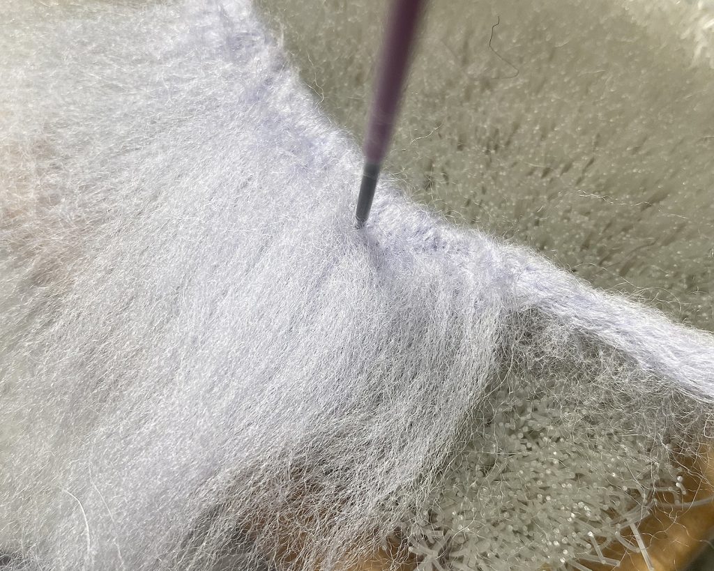 Securing long grey wool to anchor strand for mane of pony