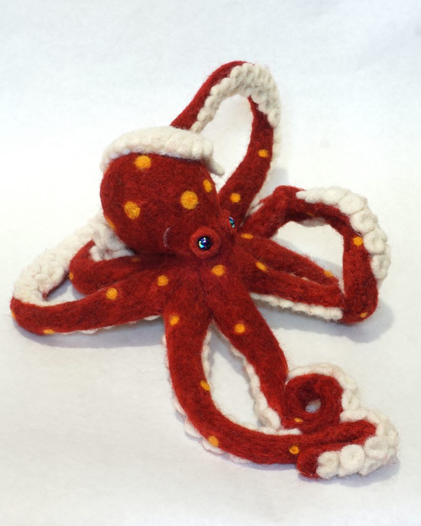 Needle felted anthropomorphic octopus sculpture holding a shell on head