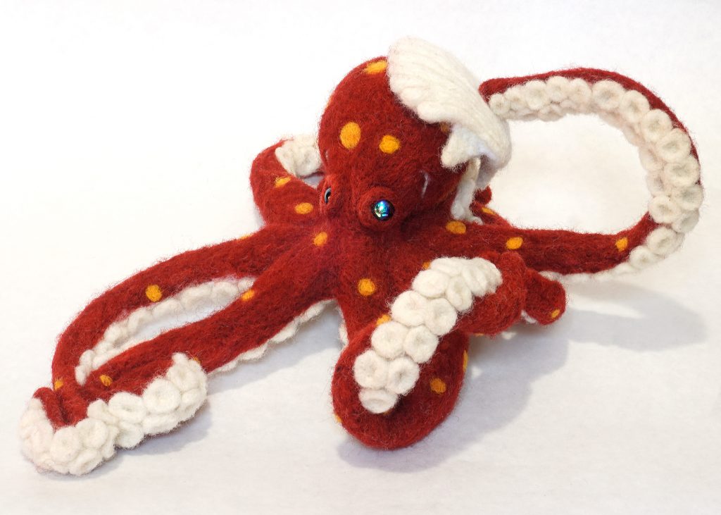 Needle felted anthropomorphic octopus sculpture holding a shell on head