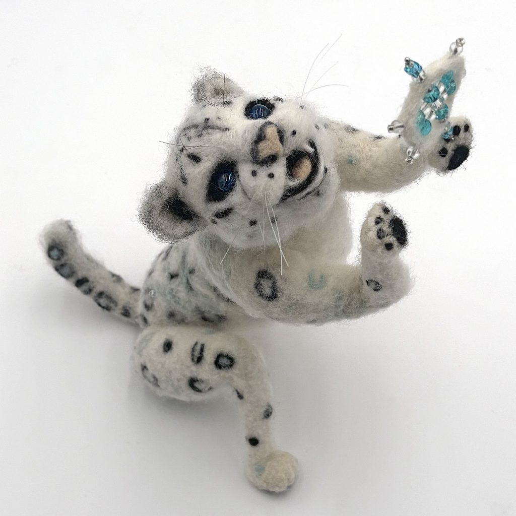 anthropomorphic holiday themed sculpture ofsnow leopard cub with with a snowflake