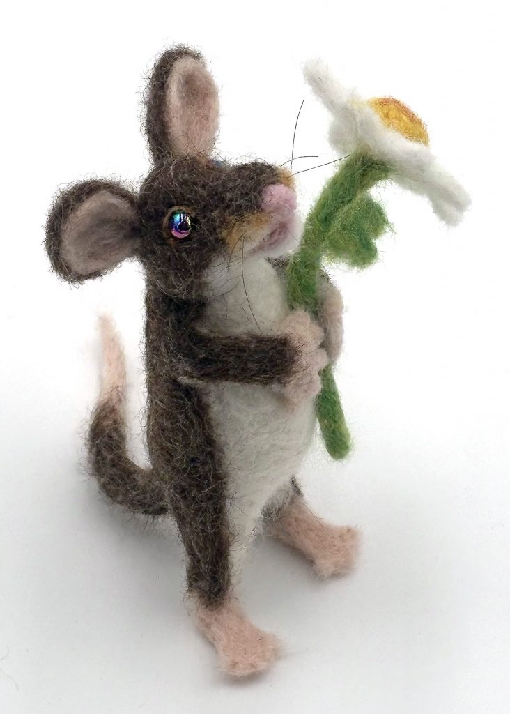 Anthropomorphic needle felted mouse sculpture by Lynn Wartski. Pnatural brown and white mouse with pink feet, hands, tail and nose holds a white and yellow daisy