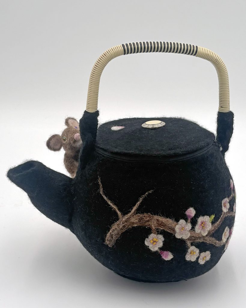 Needle and wet felted sculptural purse by Lynn Wartski. Black "teapot" with wrapped handle and sakura cherry blossom design. A small mouse peers over spout at viewer