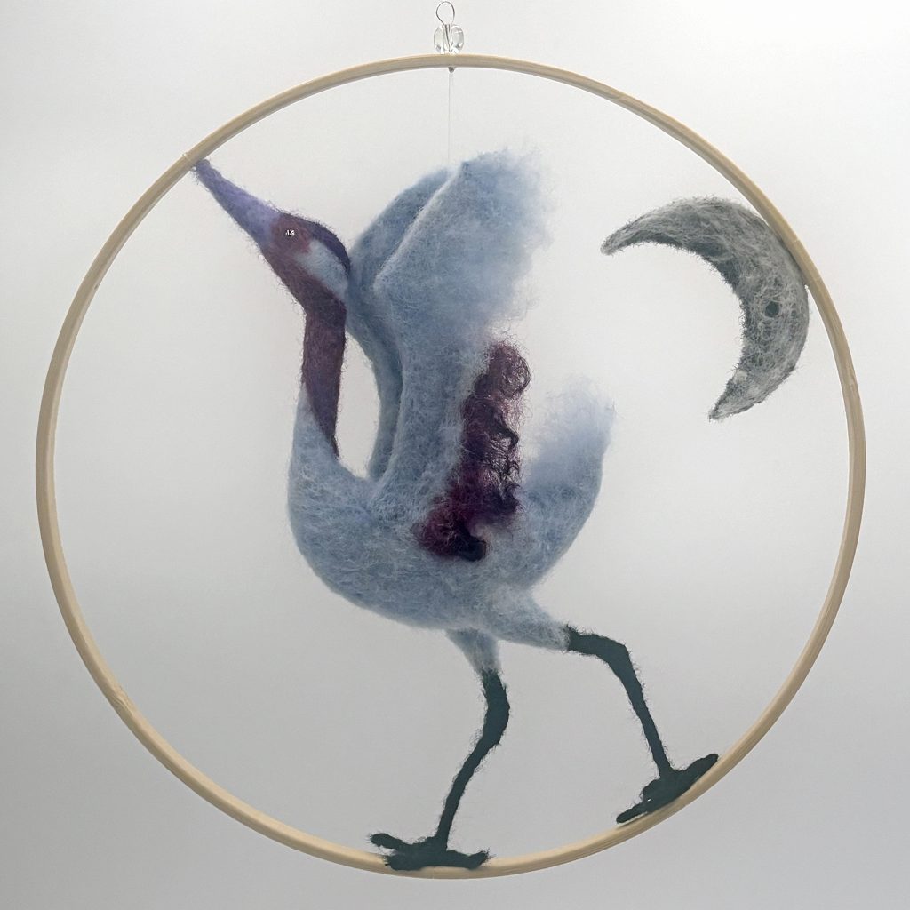 Moondance hanging sculpture by Lynn Wartski.  Needle felted crane figure in moonlit blue and magenta dances under a crescent moon.  bamboo ring frame.