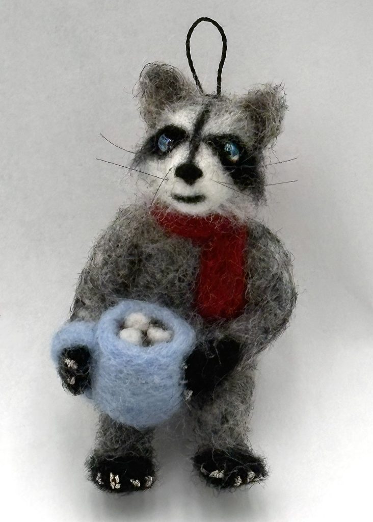 needle felted one-of-a-kind holiday ornament by Lynn Wartski. Raccoon with red scarf and blue mug of cocoa